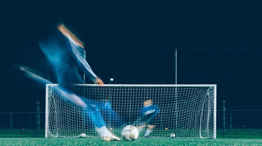 Men playing football hitting a goal