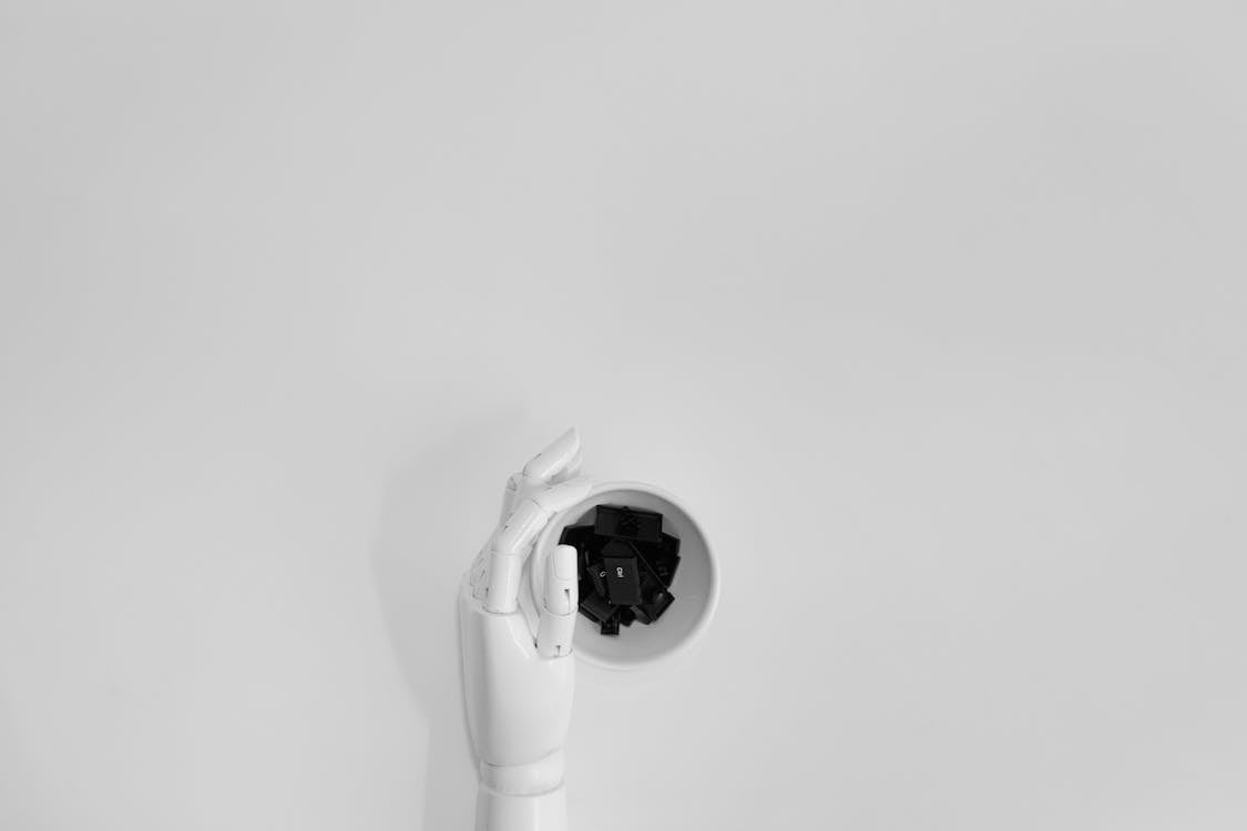 Free A robotic hand grasping black keyboard keys in a minimalist setting. Stock Photo